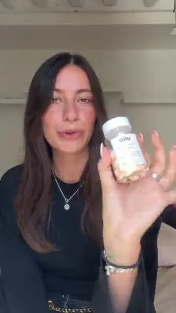 Créatrice face caméra montrant un pot de capsules Olie