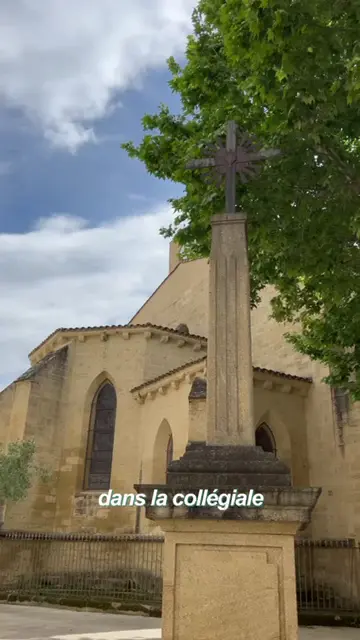 Croix de pierre devant une collégiale, sous un ciel nuageux