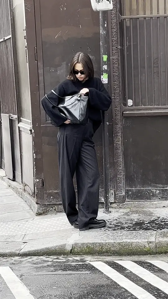 Silhouette tout en noir avec un sac en cuir, dans une rue de Paris